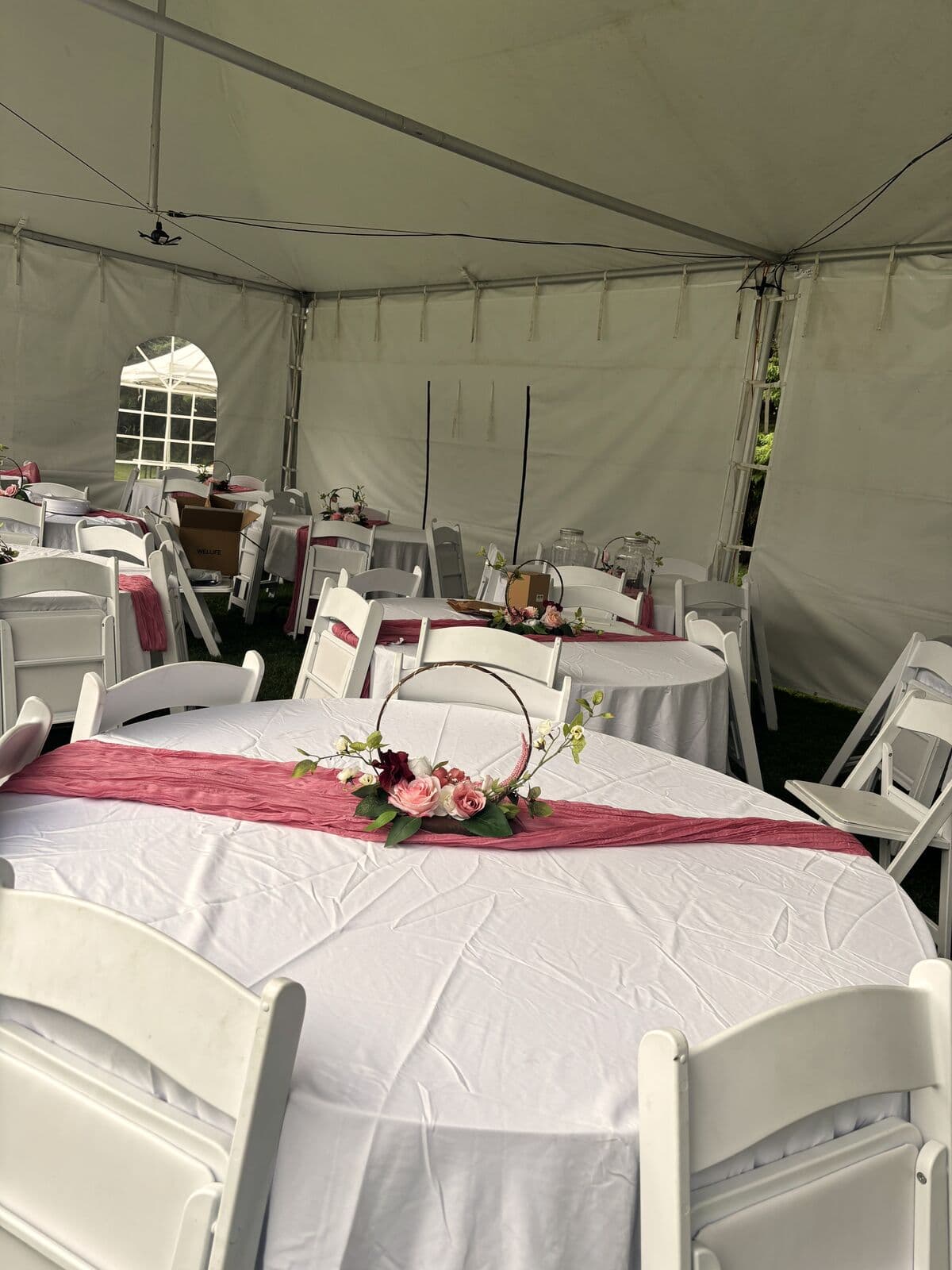 Round table with a rose runner and floral hoop, more tables behind
