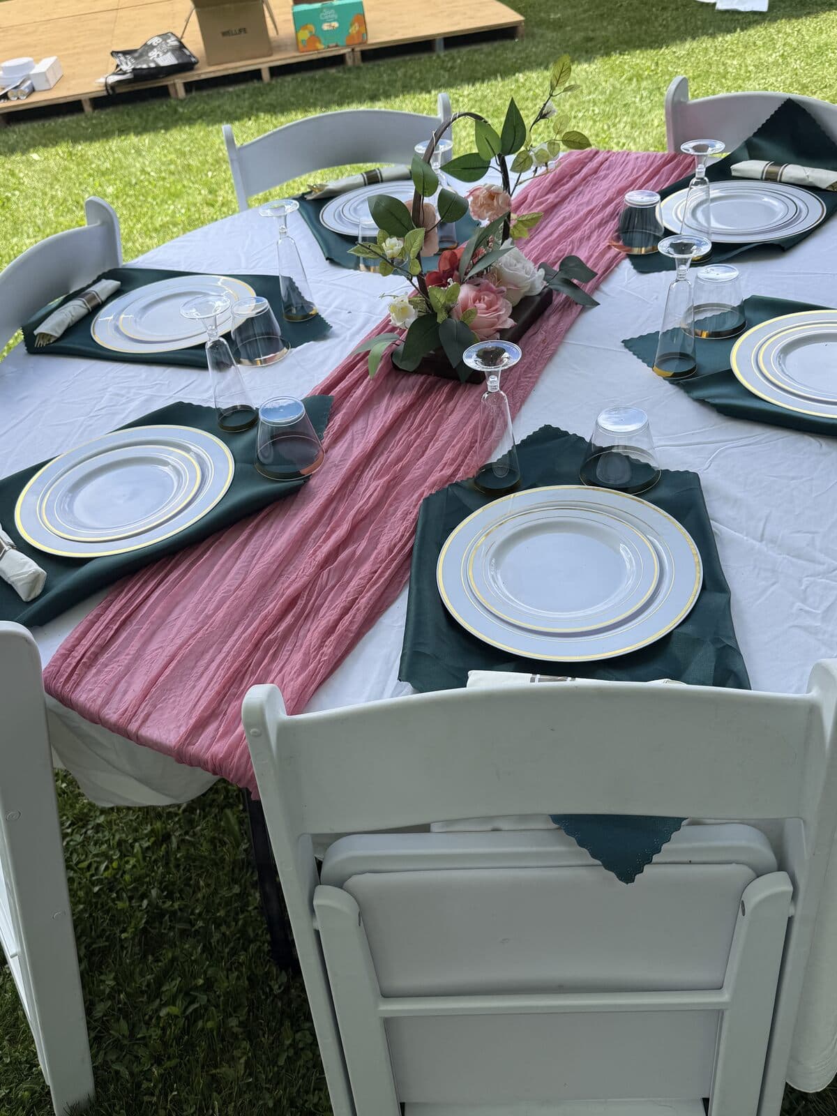 Close-up of a place setting with a rose runner under an event tent at Rustic Hideaways
